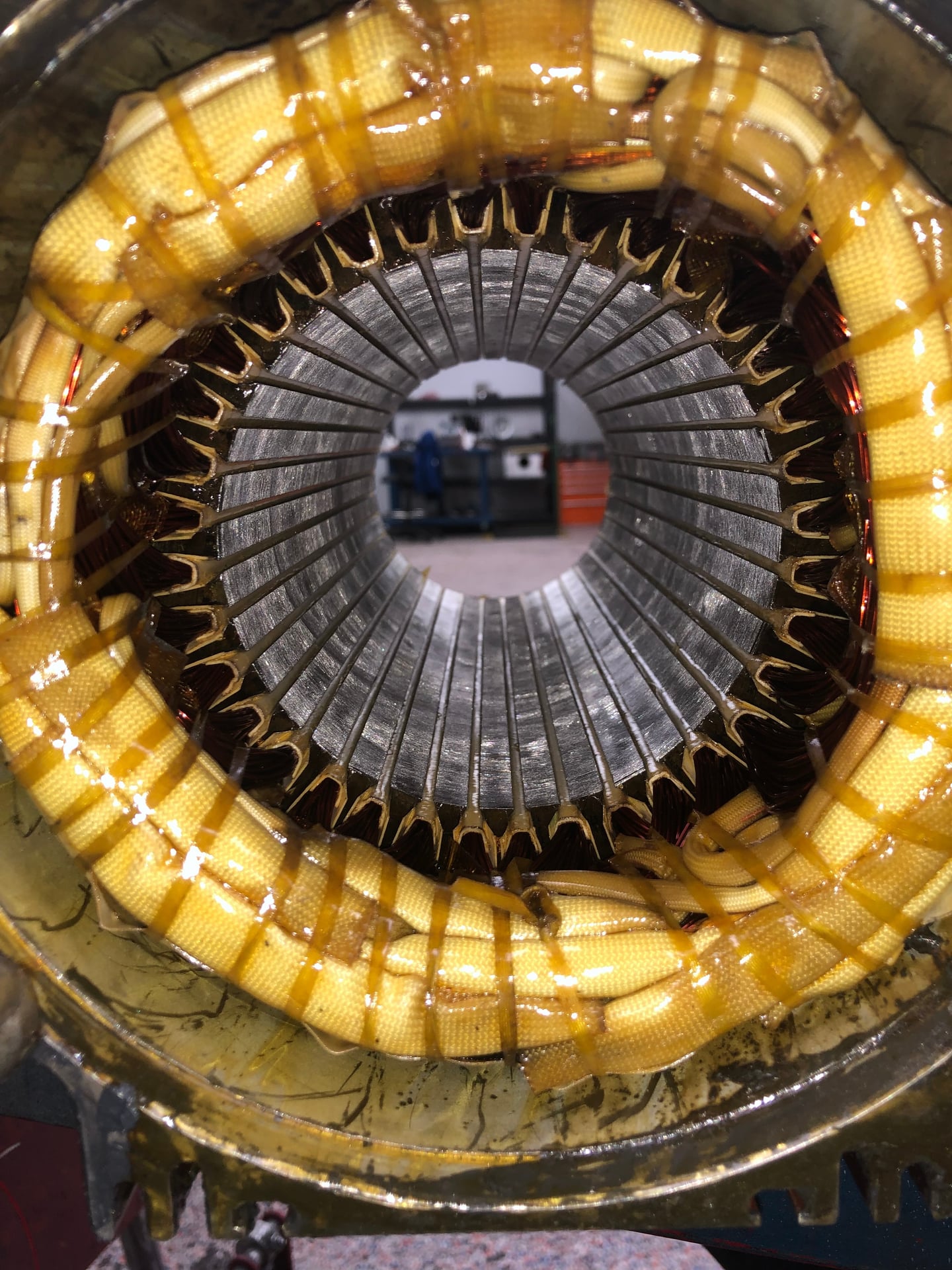 Electric motor stator with yellow insulation, circular metal core with radial slots